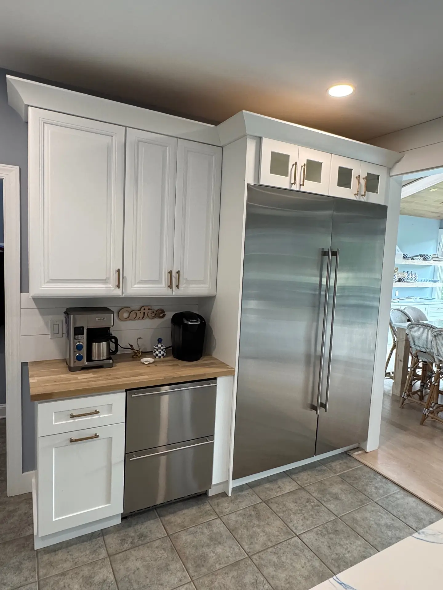 Built-in stainless refrigeration framed by white cabinetry and a coffee counter
