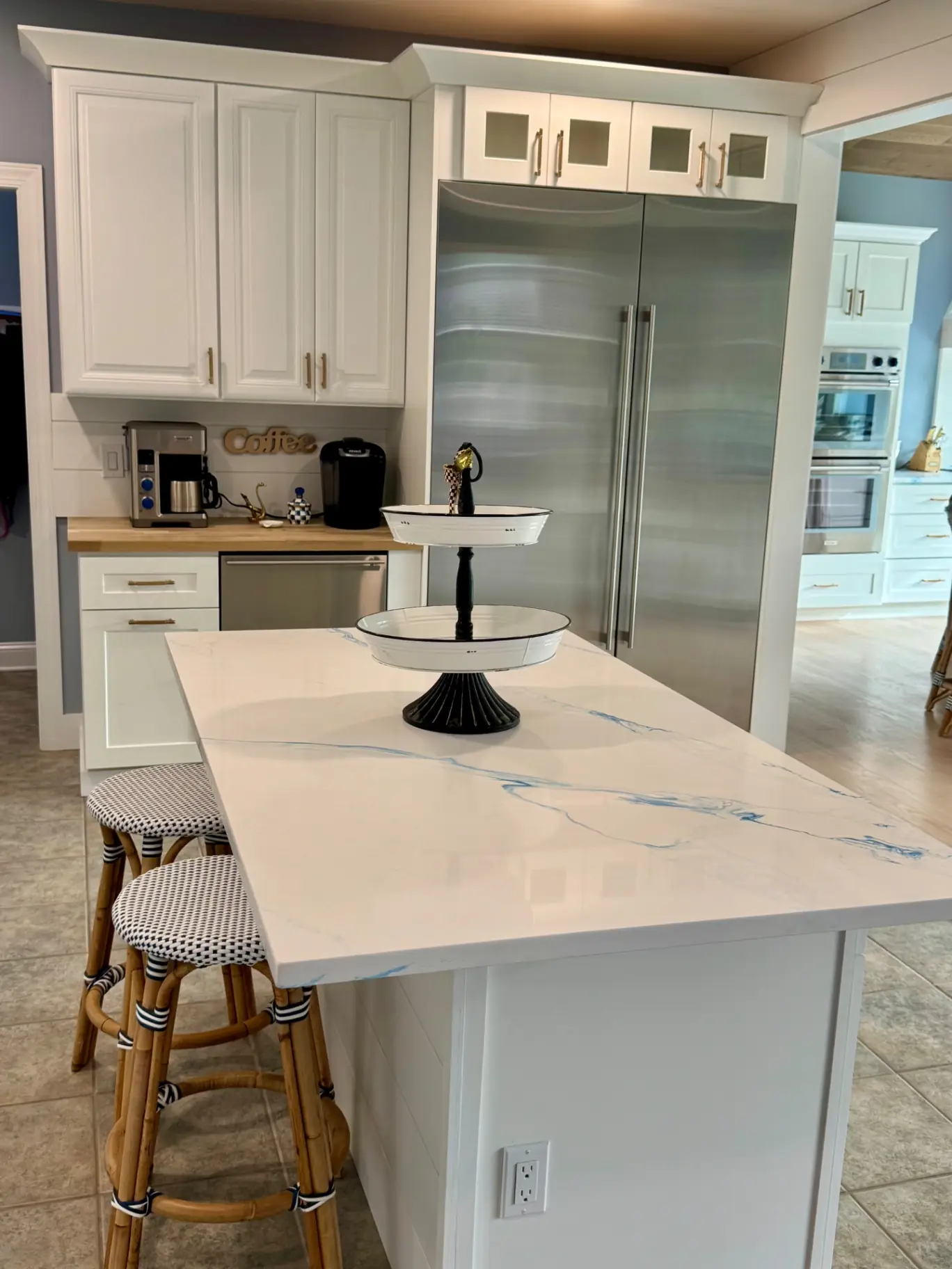 Coffee station beside a quartz island with woven counter stools