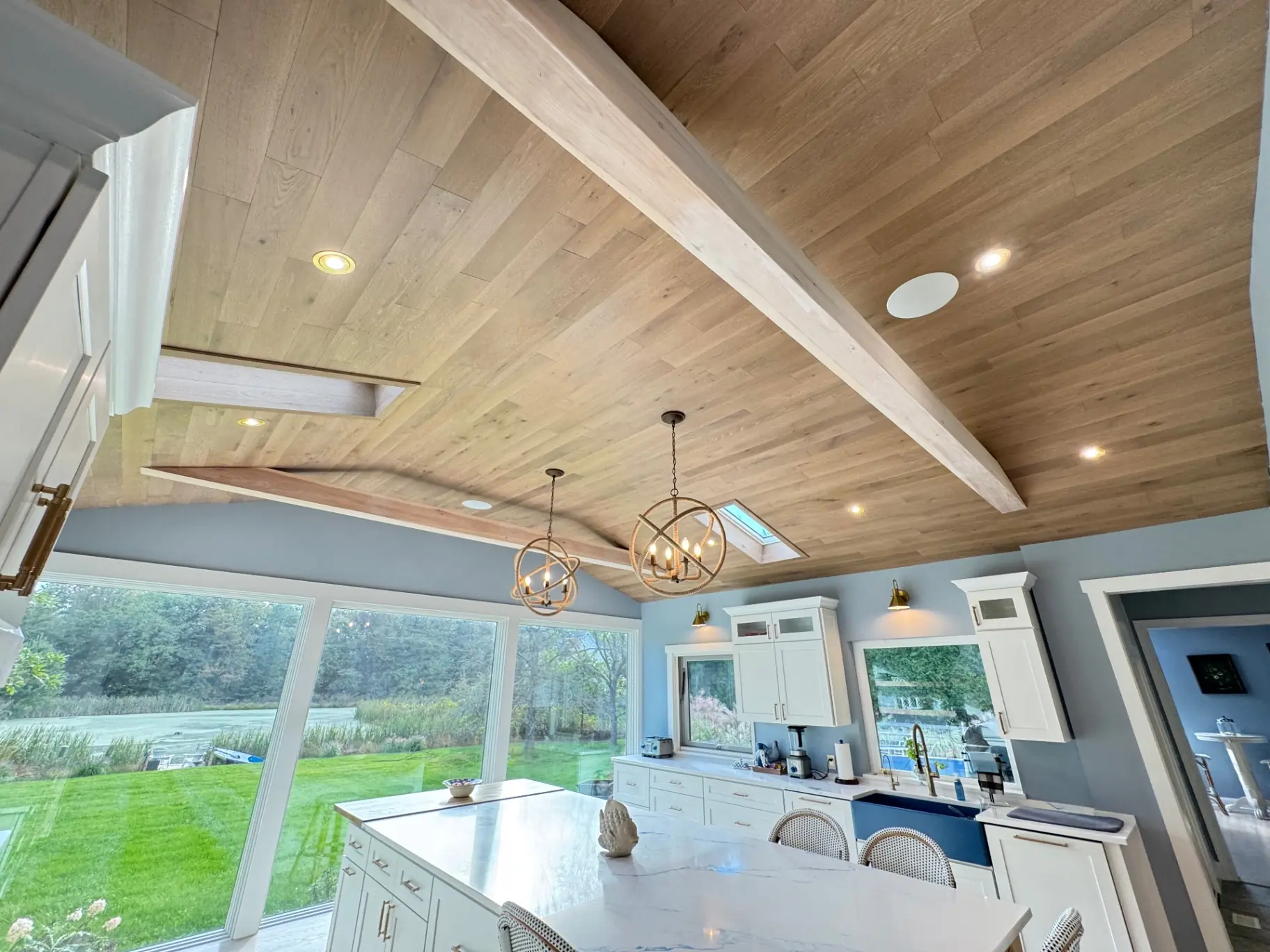 Wood-plank kitchen ceiling with exposed beams, skylights and pendant lighting
