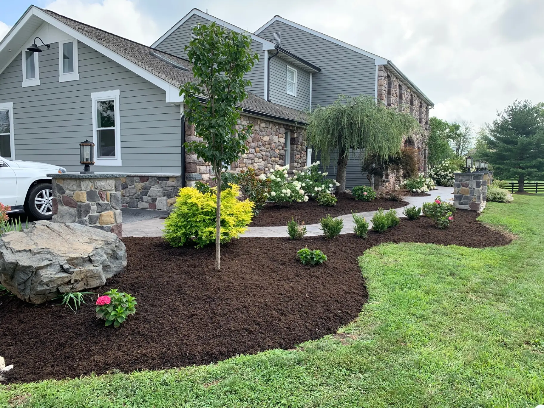 Entry pillar, boulder bed and stamped concrete walkway at the driveway in daylight, Buckingham, PA
