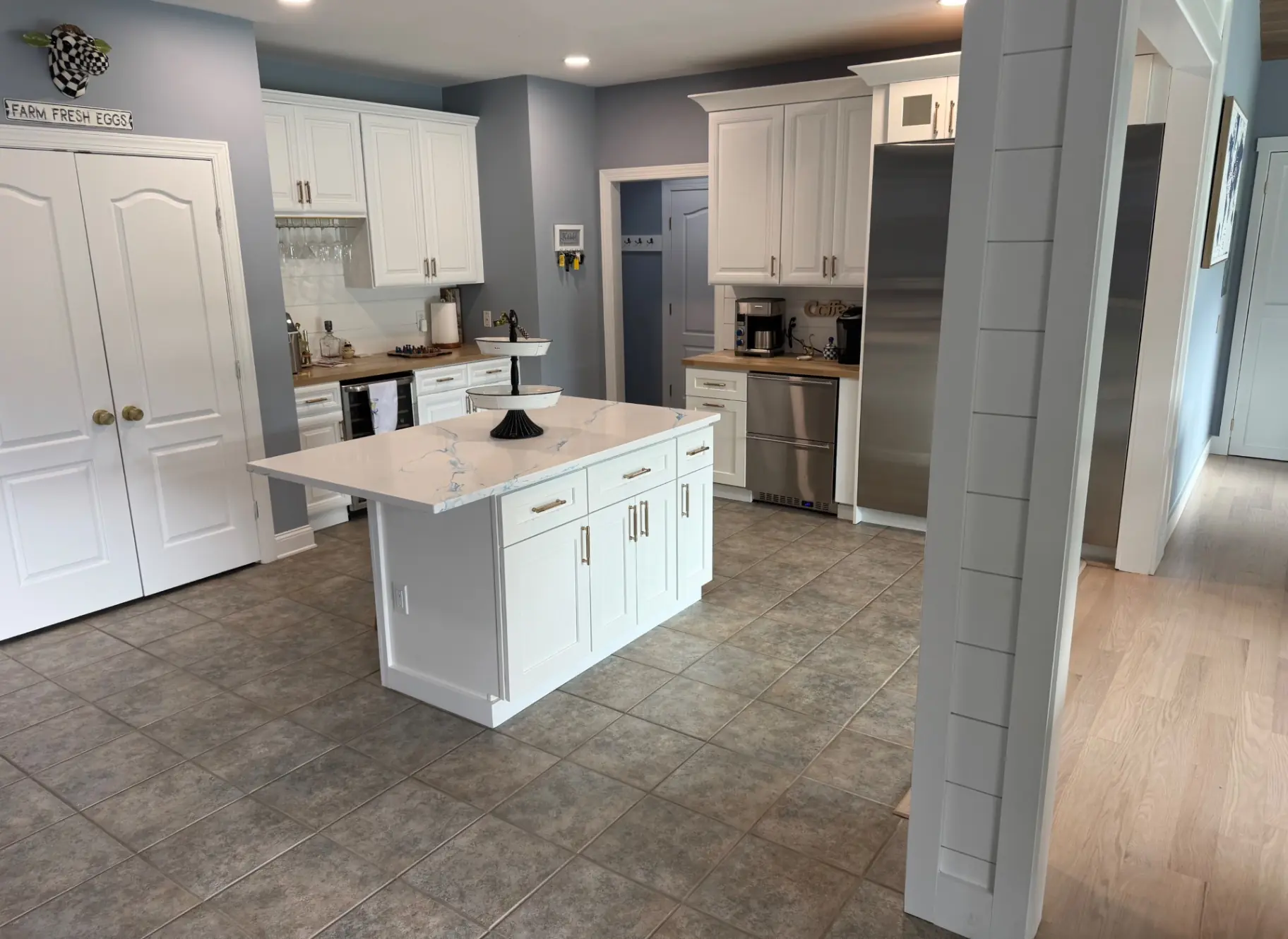 Secondary island with white cabinetry and quartz top in the adjoining space